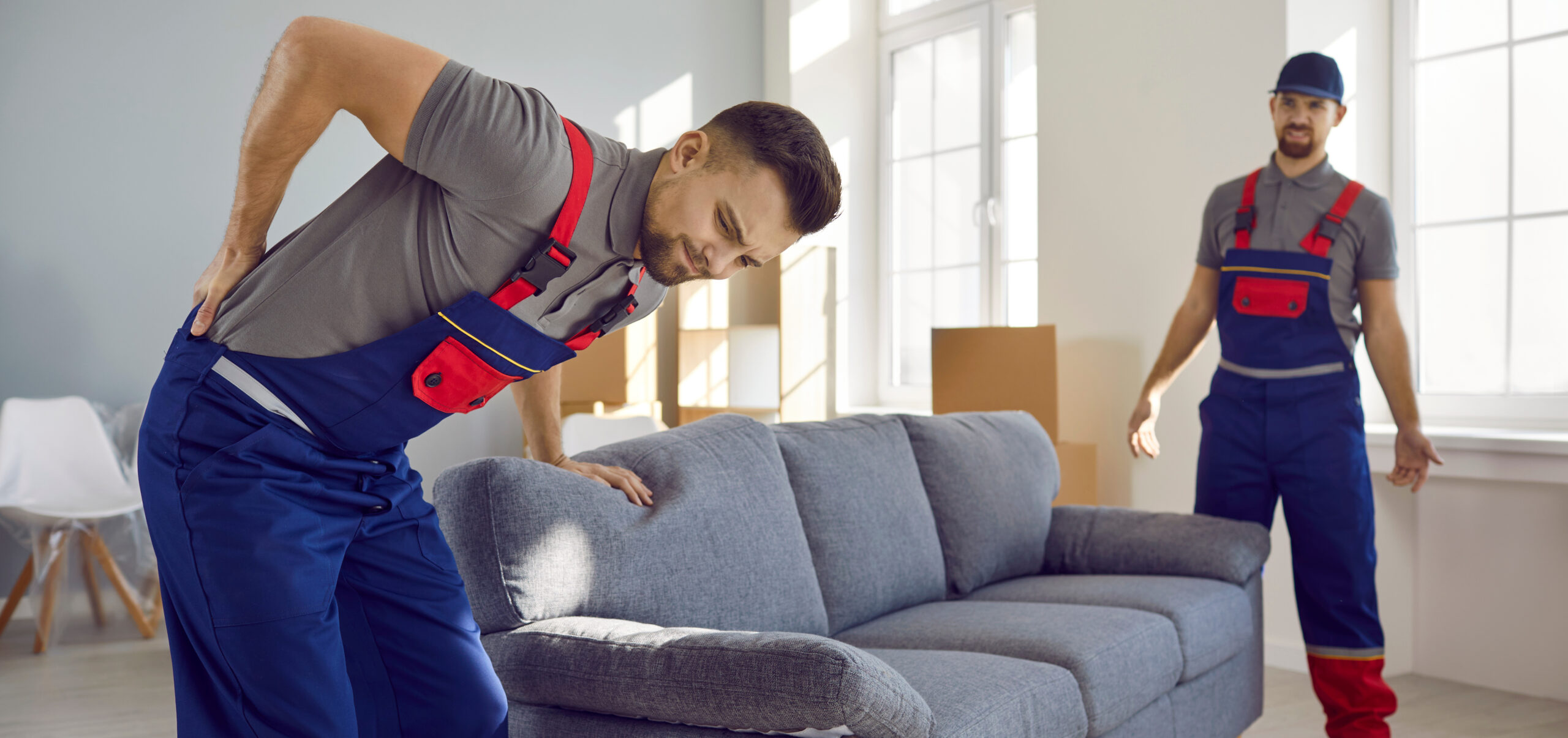 Delivery service worker feels pain in his lower back when he tries to lift a heavy sofa