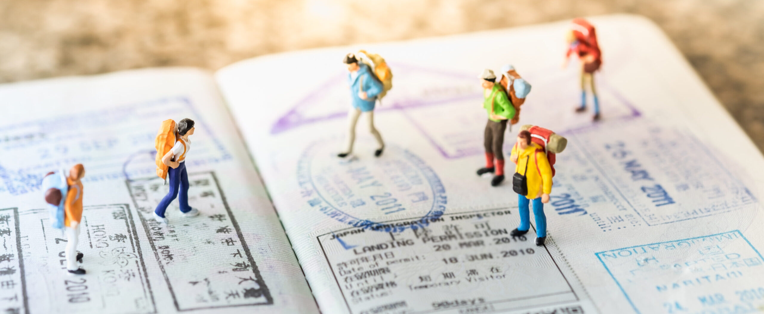 Travel Concept. Group of miniature with backpack walking and standing on passport with immigration stamps. Travel Concept. Group of miniature with backpack walking and standing on passport with immigration stamps.